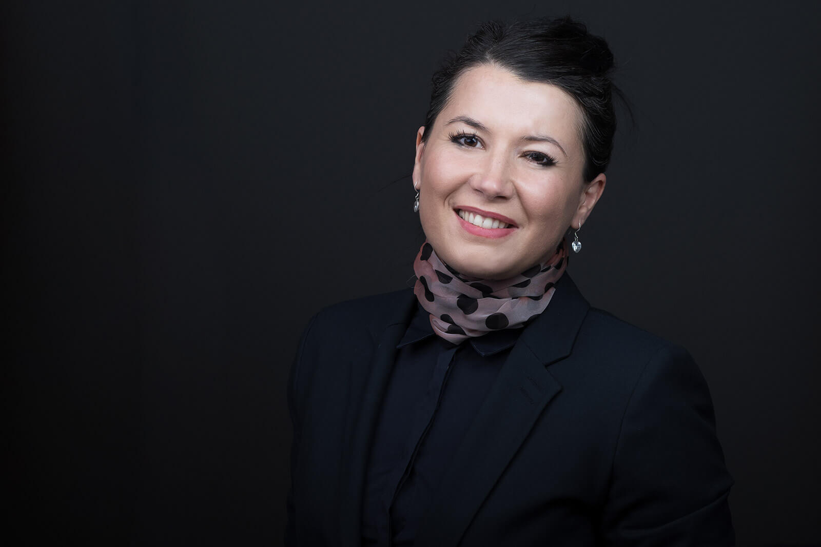 Bewerbungsfoto einer Frau auf schwarzem Hintergrund