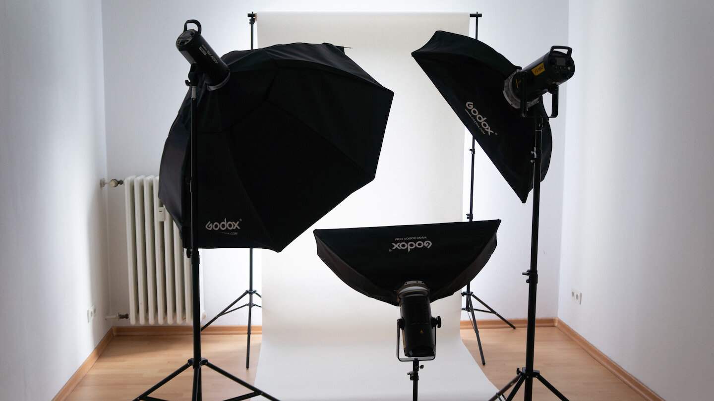 Helles Fotostudio mit drei Lampen und weißem Hintergrund